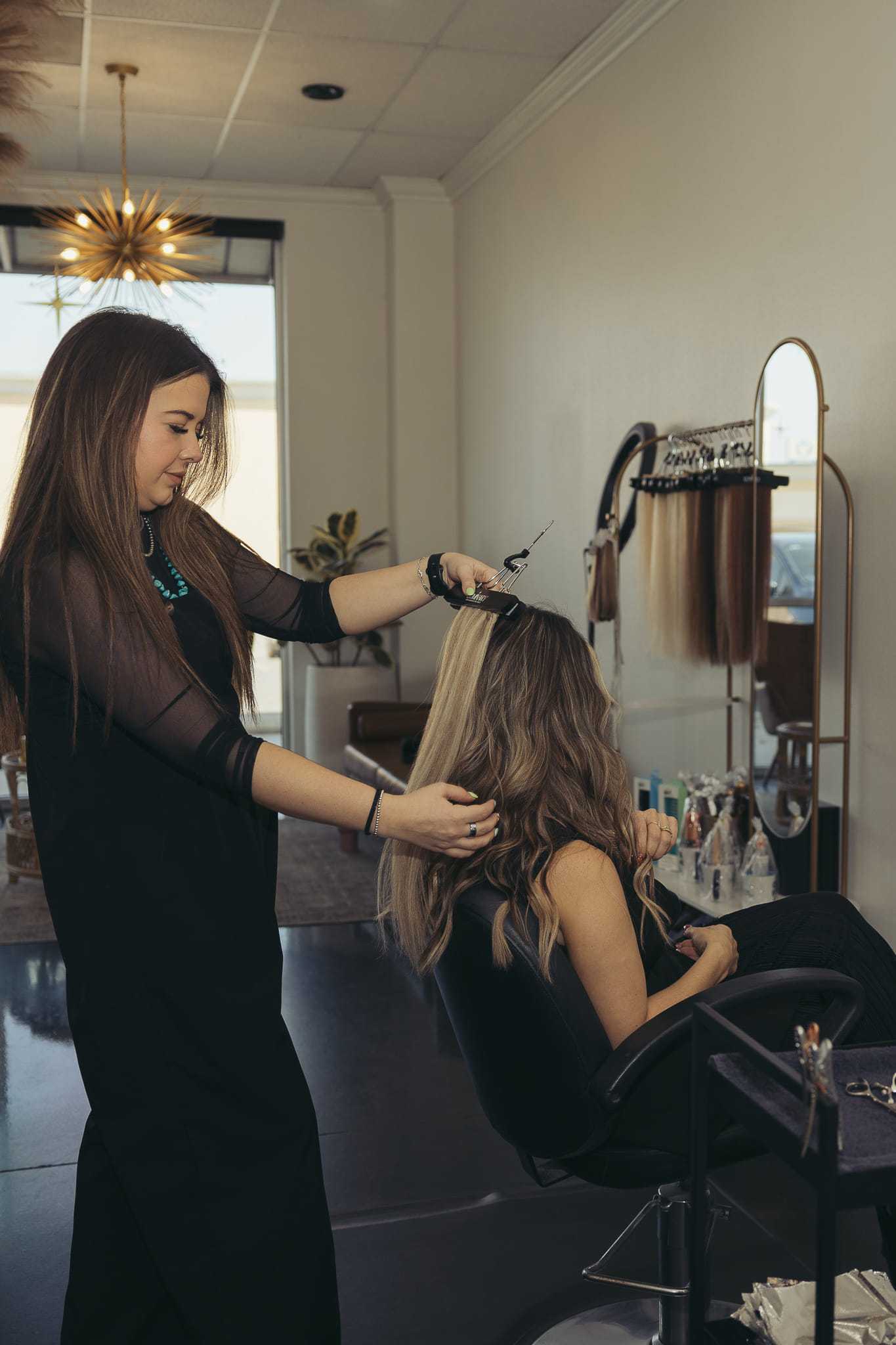 Hairstylist cutting a woman's hair in a modern salon setting.