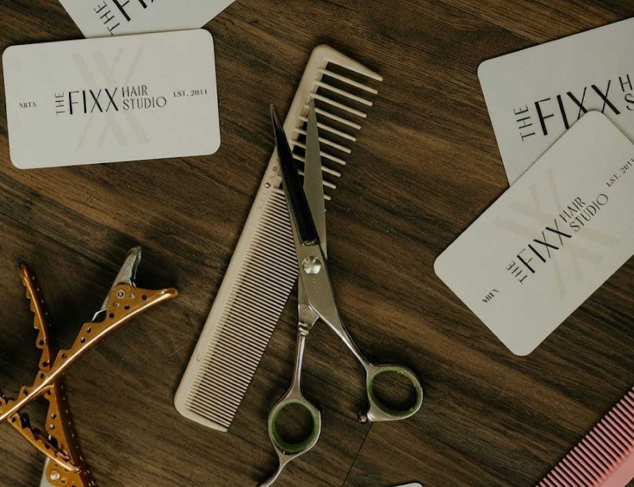 Hair styling tools and Fixx Hair Studio cards on a wooden surface.