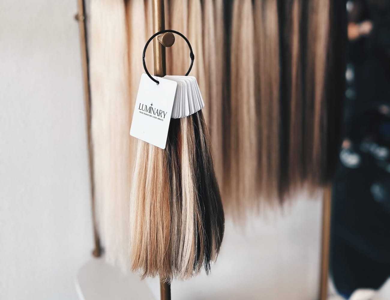 Hair extensions of various shades on display with a sample swatch for selection.