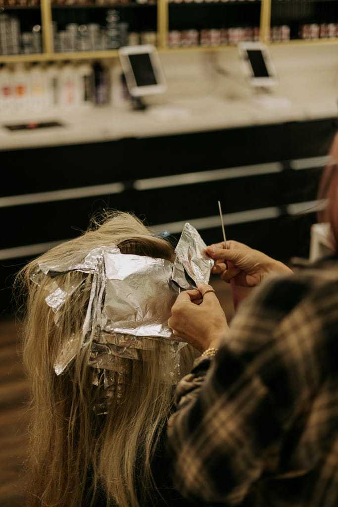 Hairdresser applying foils for highlights in a salon setting.